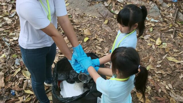 Group of Asian volunteer families put their hands together before picking up trash littered by the river. Put garbage in the bin to help save the environment. World Environment Day