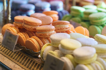 Assortment of colorful french macaroons on cafe showcase for sale . Variety of macaron flavours. Sweet almond cakes in store. Cookies in the shop on storefront