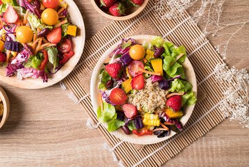Obraz na płótnie Canvas Fresh mixed fruits and vegetables salad in natural plate on wooden background, Healthy vegan food, Table top view