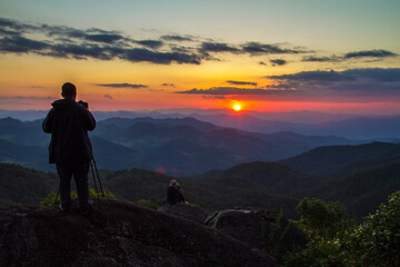 silhouette of a man standing on a mountain top at sunset