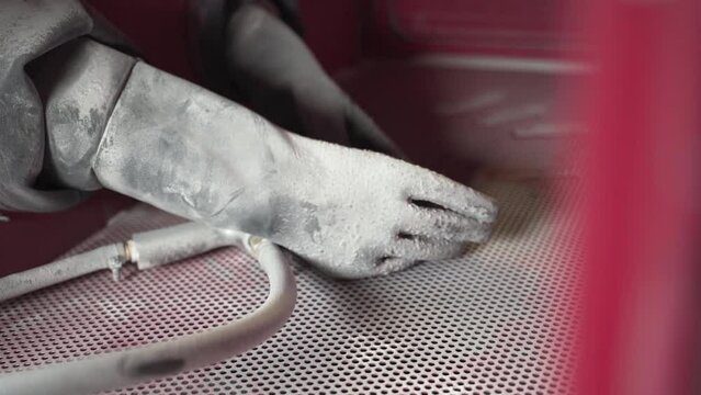 Protective rubber gloves and blasting gun in a sandblasting cabinet.