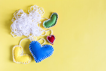 The concept is a ball of white threads with colored hearts tied on a yellow background.