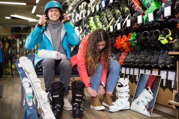 Customer male and female are trying on boots for skiing in a sportswear store
