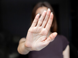 Close-up focus on a woman showing a stop gesture to the camera, blurred background, a strong young...