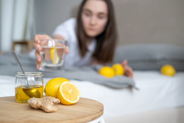 The girl in the background drinks healthy water with lemon. Lemon, honey and ginger for health and...