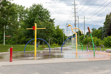 Fototapeta na wymiar Splash pad playground in public park in summer without people. Fountain with splashing water