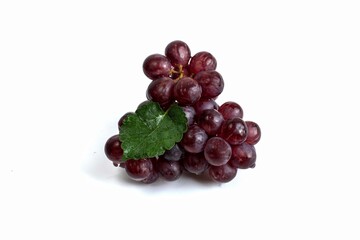 Red grapes, dark sweet fruit bunches with green leaves on a white background.