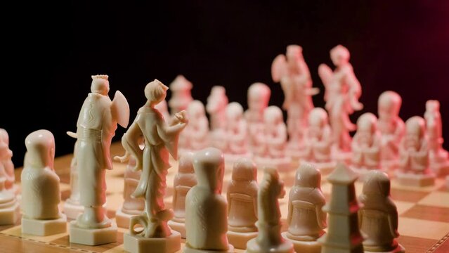 A close up dolly shot tracking in onto a chessboard, as the hand of a player makes his first strategic move advancing his pawn forward signifying the start of a new game of chess 