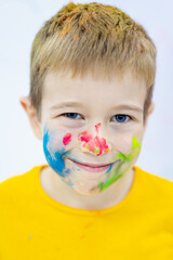 a small child boy stained and painted with paint, a portrait of a dirty happy child in multi-colored paint