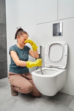 Woman Covering Nose To Avoid Bad Smell While Cleaning A Smelly Toilet Bowl