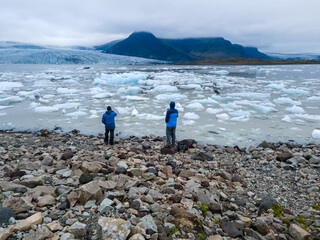 View tourists contemplating the  massive Glacier in Iceland and its lagoon caused by global warming -Svinafellsjokull - Jökulsárlón