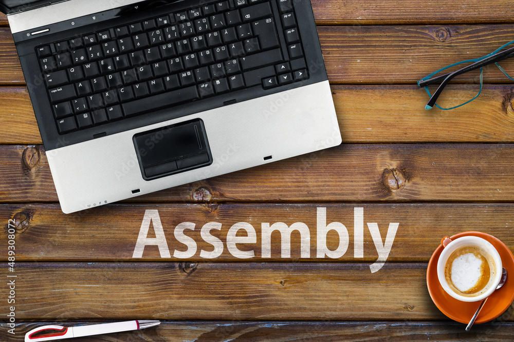 Poster assembly programming language. word assembly on wooden desk and laptop