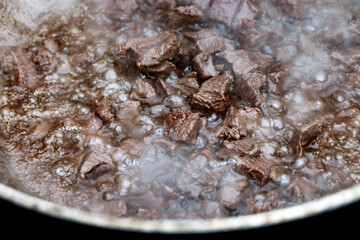 Pieces of meat for pilaf are stewed in cauldron