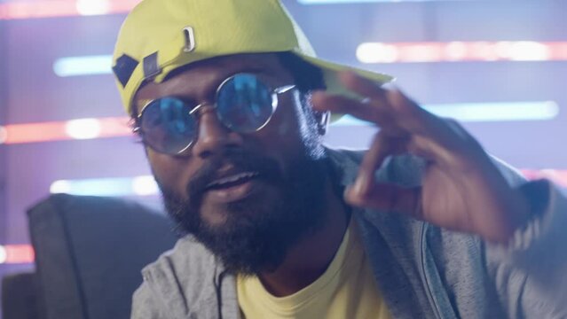 close up shot of hip hop rapper singing by looking at camera on neaon background - concpet of hip hop music, professional singer and entertainment