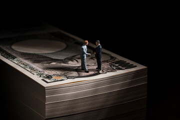 お金（札束）とミニチュアのビジネスマン