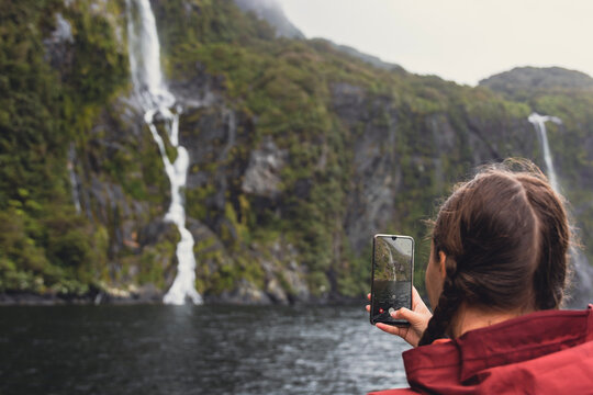 person taking a picture of waterfall
