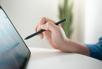 Close up of hand using digital pen on digital tablet