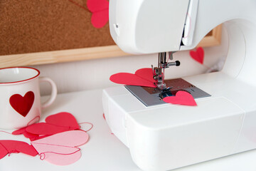 Sewing machine and paper hearts. The process of making a garland. Concept to sew with love, Valentines Day.