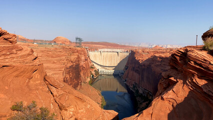 Glen Canyon Dam in Page, Arizona on a a hot sunny day. The dam forms the man-made lake Powel, on of the largest reservoirs in the USA. Colorado river carved the riverbed in the red Navajo stone.