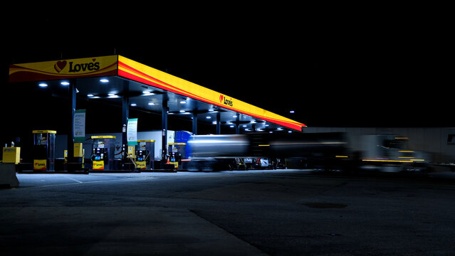 Love's gas station at night with semi trucks parked in fuel islands, fueling 