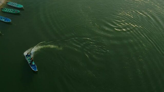 Aerial follow shot of Sightseeing Boat At Keenjhar Lake In Thatta, Pakistan at sunset.