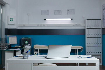 Empty doctor office with nobody in it equiped with medical equipment having laptop on desk. Modern...