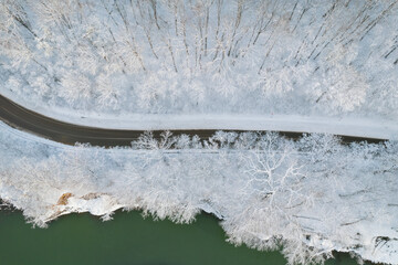Aerial top down cinematic winter snow cowered country road, asphalt serpentine. Cars go traffic...