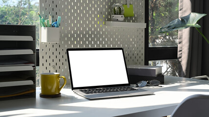 Computer laptop, coffee cup and supplies on white table at home office.
