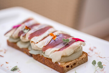 Foie gras with pear and thinly sliced duck breast Magret on the top on the home-made bread. Gourmet...