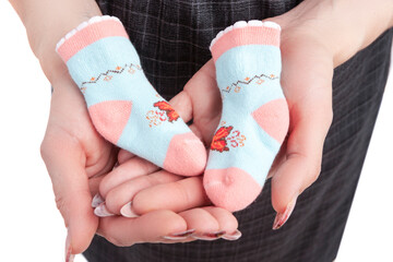 Closeup of Hands of Pregnant Woman Holding Baby Tiny Accessories Socks On Hands Isolated Over White Background.