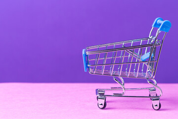 One Empty Blue Trolley Shopping or Sale Cart Placed Over Seamless Solid Purple Violet Background With Copy Space. - Powered by Adobe