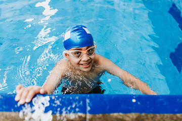 latin child boy swimmer wearing cap and goggles in a swimming training at the Pool in Mexico Latin...