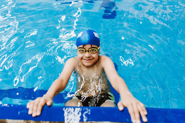 latin child boy swimmer wearing cap and goggles in a swimming training at the Pool in Mexico Latin...