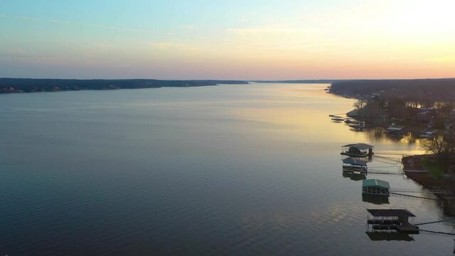 Bird Flying Across Screen Over Grand Lake at Sunrise in Midwest Oklahoma. Aerial Drone Flyover of Floating Docks witt Roofs for Fishing Activity and Lake Houses