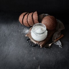 Coconut panna cotta glass jar with coconut shells on a black background with space for text. Top view