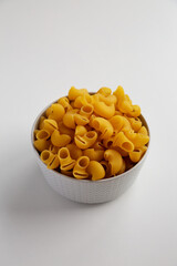 Raw Dry Organic Pipe Rigate Pasta in a Bowl on white background, side view.