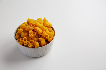 Raw Dry Organic Pipe Rigate Pasta in a Bowl on white background, side view. Space for text.