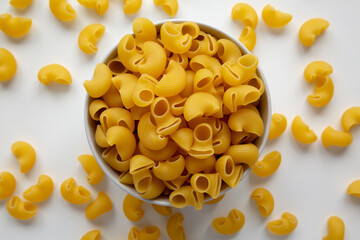 Raw Dry Organic Pipe Rigate Pasta in a Bowl on white surface, top view. Flat lay, overhead, from above.