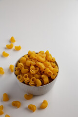 Raw Dry Organic Pipe Rigate Pasta in a Bowl on white background, side view. Copy space.