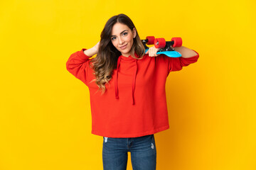 Young caucasian woman isolated on yellow background with a skate