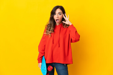 Young caucasian woman isolated on yellow background with a skate and doing surprise gesture