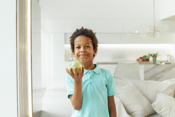 Fototapeta na wymiar Healthy eating, childhood, nutrition concept. Small boy eating green apple indoor