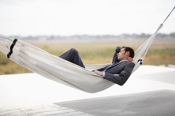 Taking in the landscape. A young executive in a suit taking in the landscape from a hammock.
