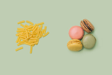 Artisan chef minimal concept. Raw macaroni on the left and four yummy macarons  on the right side. Flat lay arrangement with pastel green background