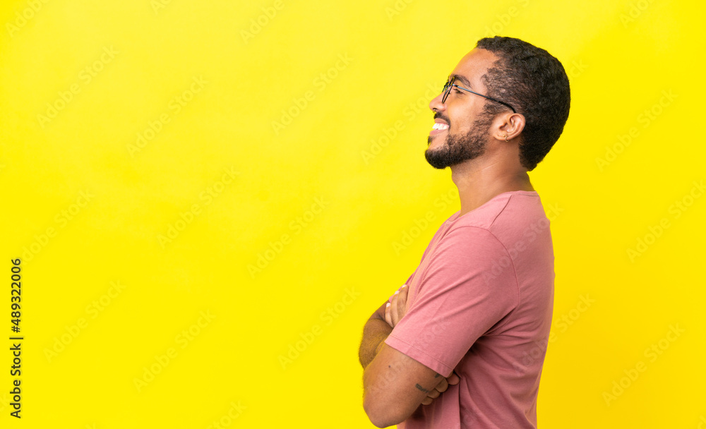 Wall mural young latin man isolated on yellow background in lateral position