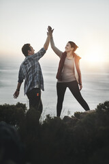 This couple conquered the mountain. Shot of a young couple high fiving after making it to the top...