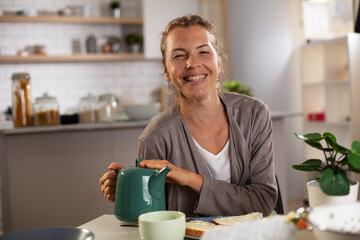 Beautiful woman enjoying in breakfast. Happy young woman eating sandwich at home