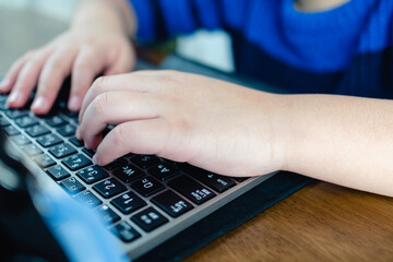 ノートパソコンのキーボードと小学生の子供の手