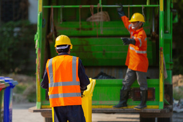 Garbage collector, teamwork garbage men working together on emptying dustbins for trash removal with truck loading waste and trash bin.