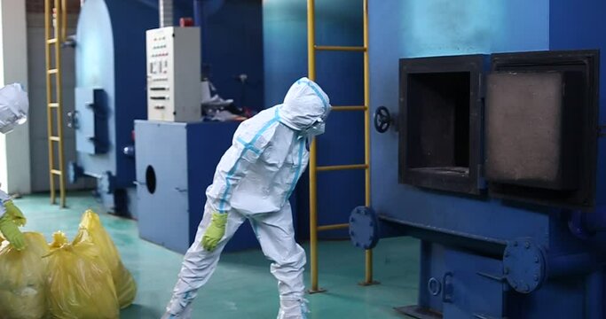 Workers are loading garbage into the incinerator by wearing protective clothing complete with masks